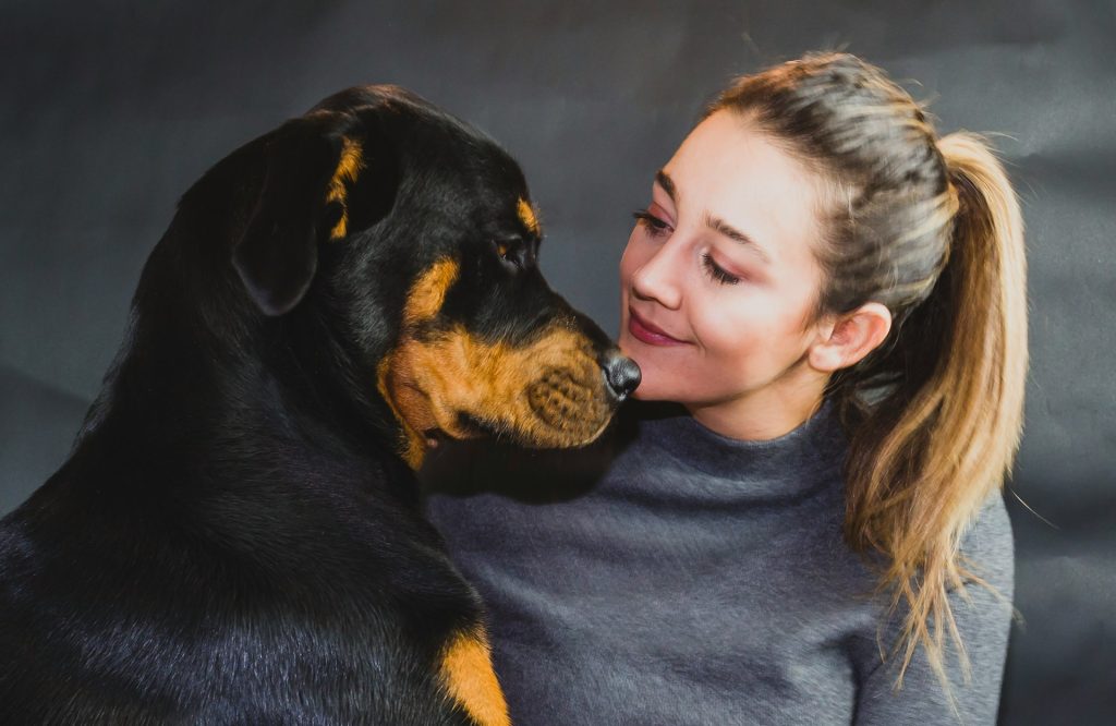 A woman is face to face with her dog smiling.